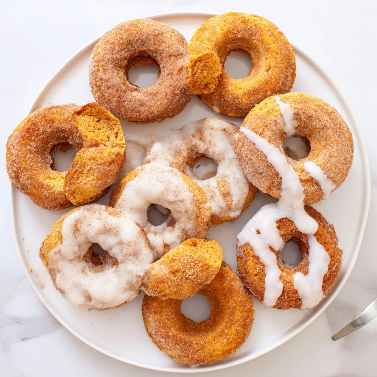 Golden fried pumpkin spice biscuit donuts coated in cinnamon sugar with sweet vanilla glaze drizzle