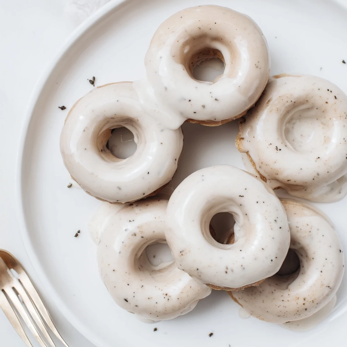 Golden brown Earl Grey mochi donuts with sweet white glaze drizzling over chewy ring shapes