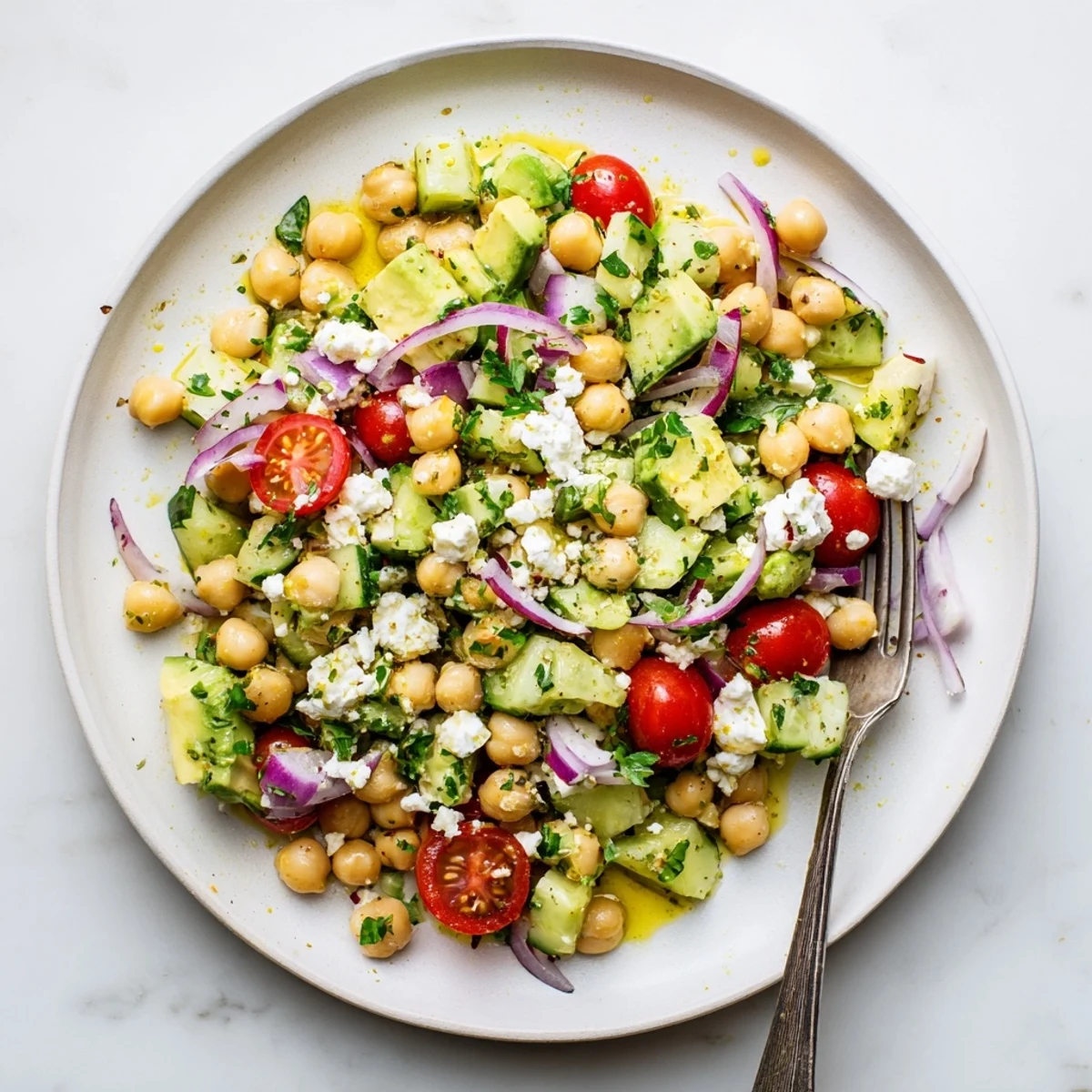 Mediterranean chickpea feta avocado salad featuring ripe avocado, crumbled feta, and crisp cherry tomatoes