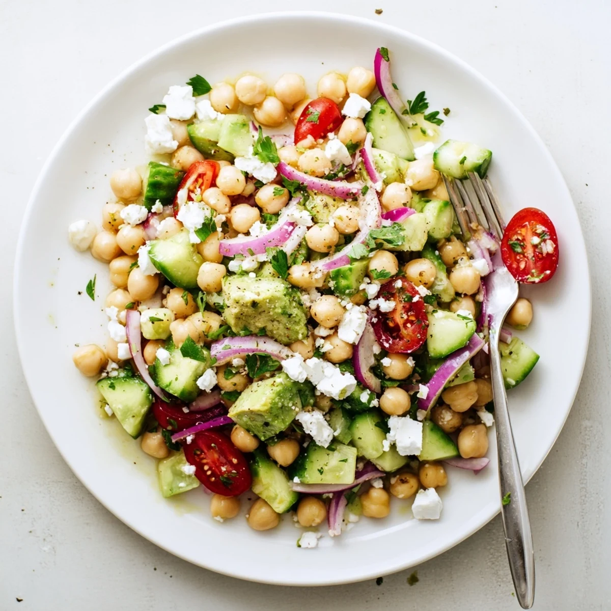 Colorful chickpea feta avocado salad bowl loaded with fresh vegetables and zesty lemon dressing