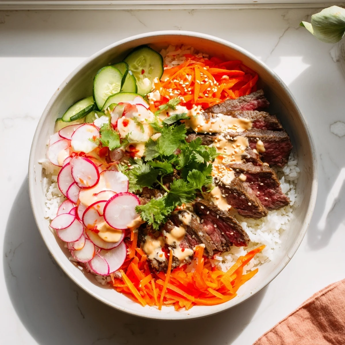 Tender Korean BBQ steak slices draped over fluffy white rice with crisp colorful vegetable toppings and creamy spicy sriracha drizzle