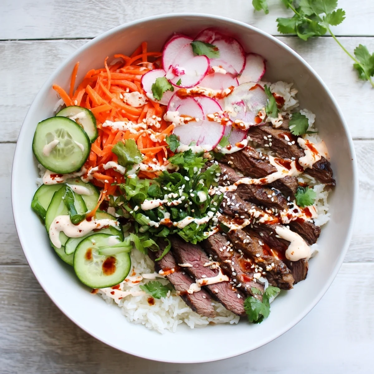 Caramelized Korean BBQ flank steak served in a rice bowl with fresh cucumber radishes and tangy spicy cream sauce