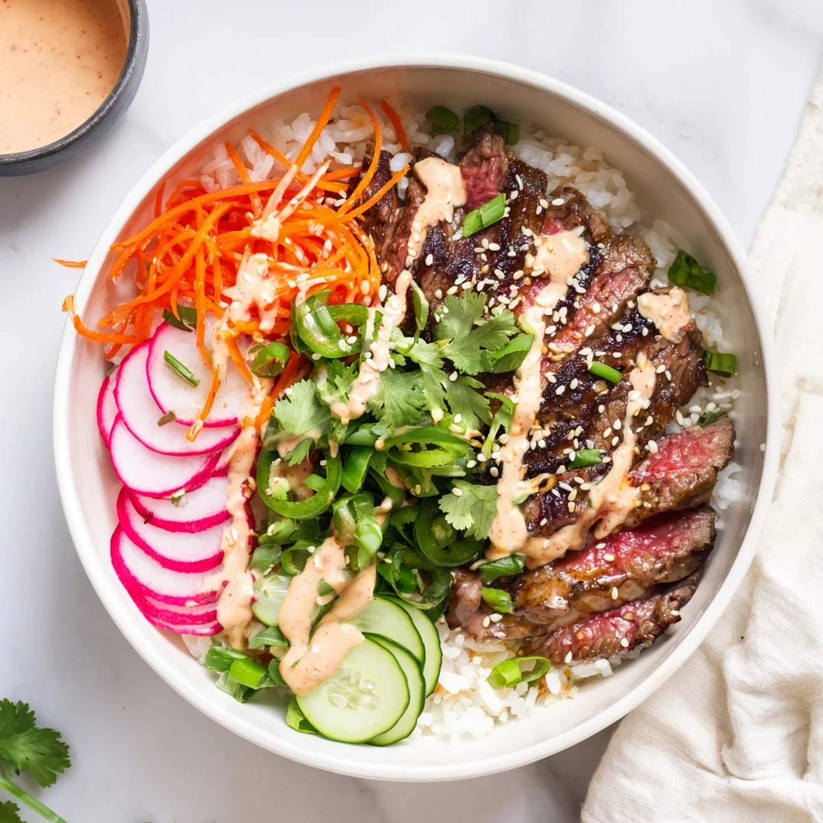 Close up of Korean BBQ steak rice bowl featuring marinated meat shredded carrots spring onions and zesty gochujang mayo