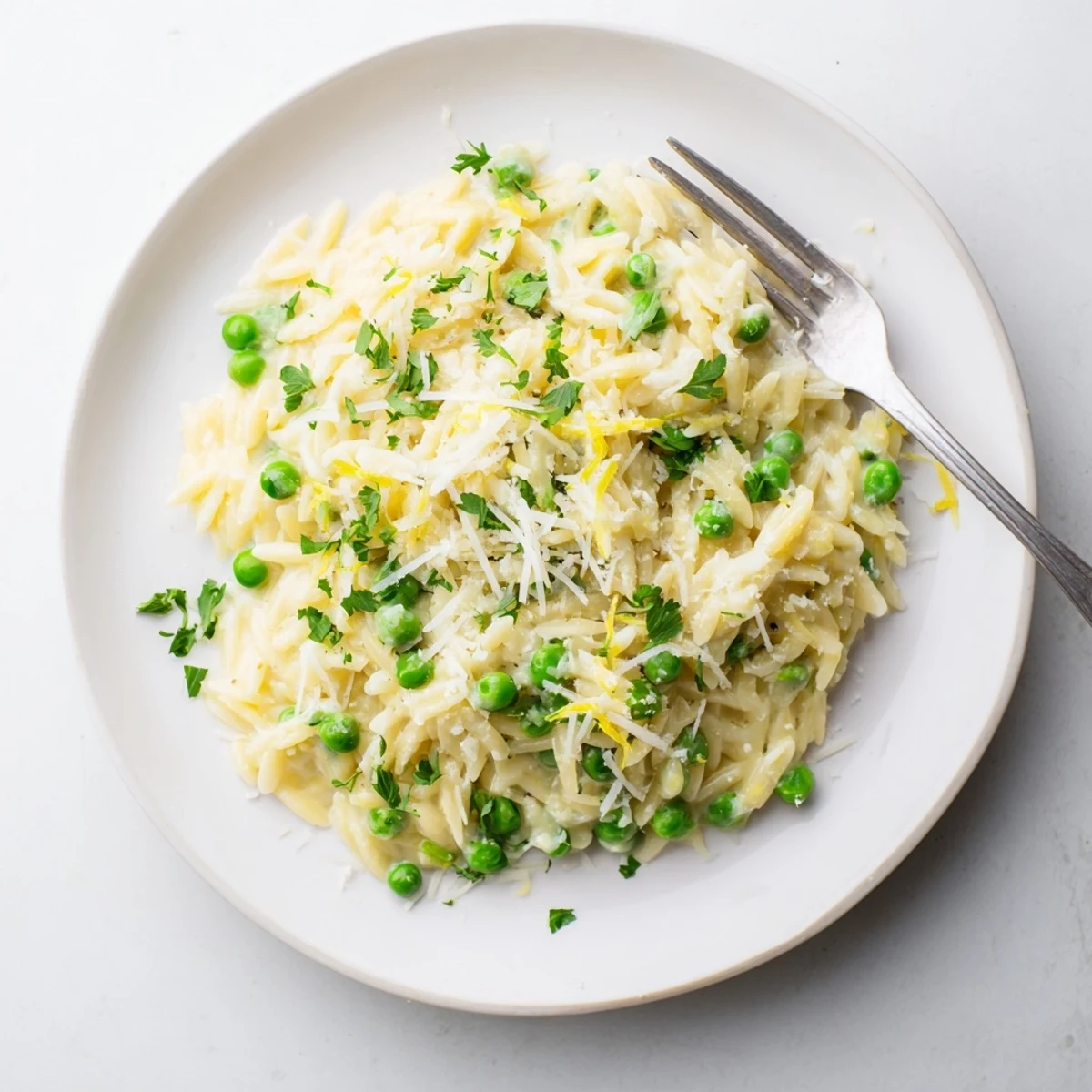 Creamy lemon orzo pasta with fresh parsley and grated Parmesan cheese in a white bowl