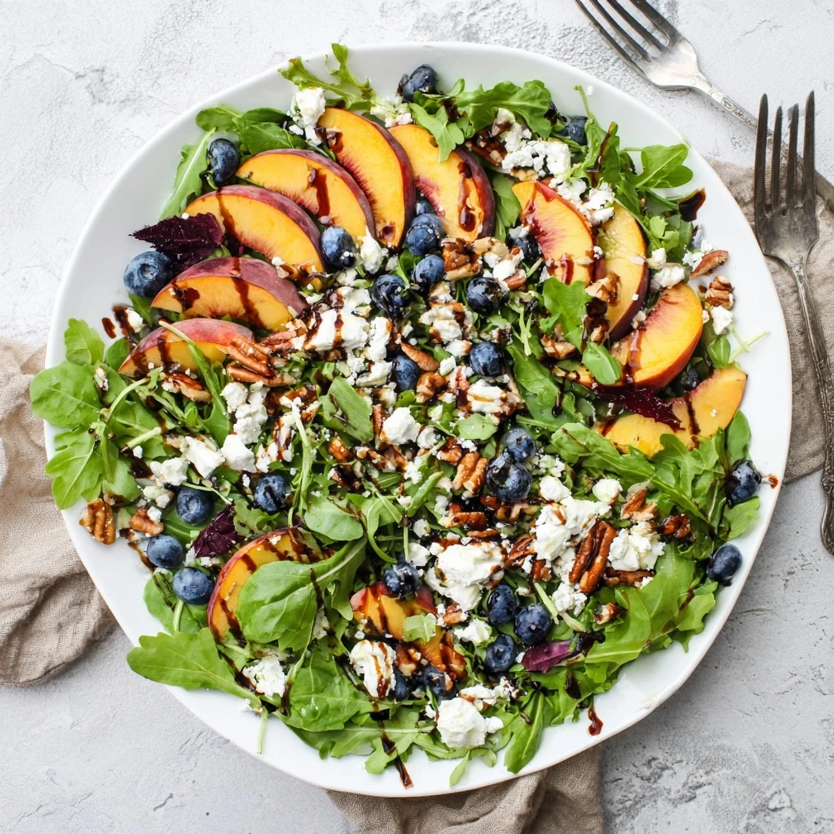 Colorful blueberry peach feta salad showcasing fresh summer fruits and creamy cheese atop crisp mixed greens