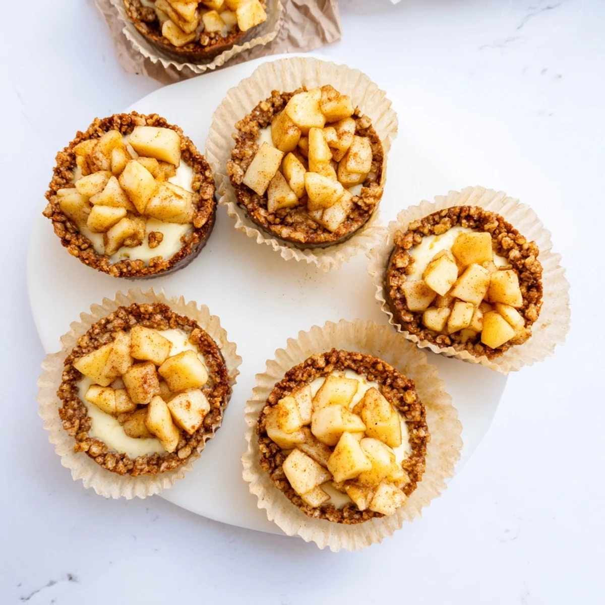 Golden baked apple crisp mini cheesecakes with graham cracker crust and cinnamon-spiced topping