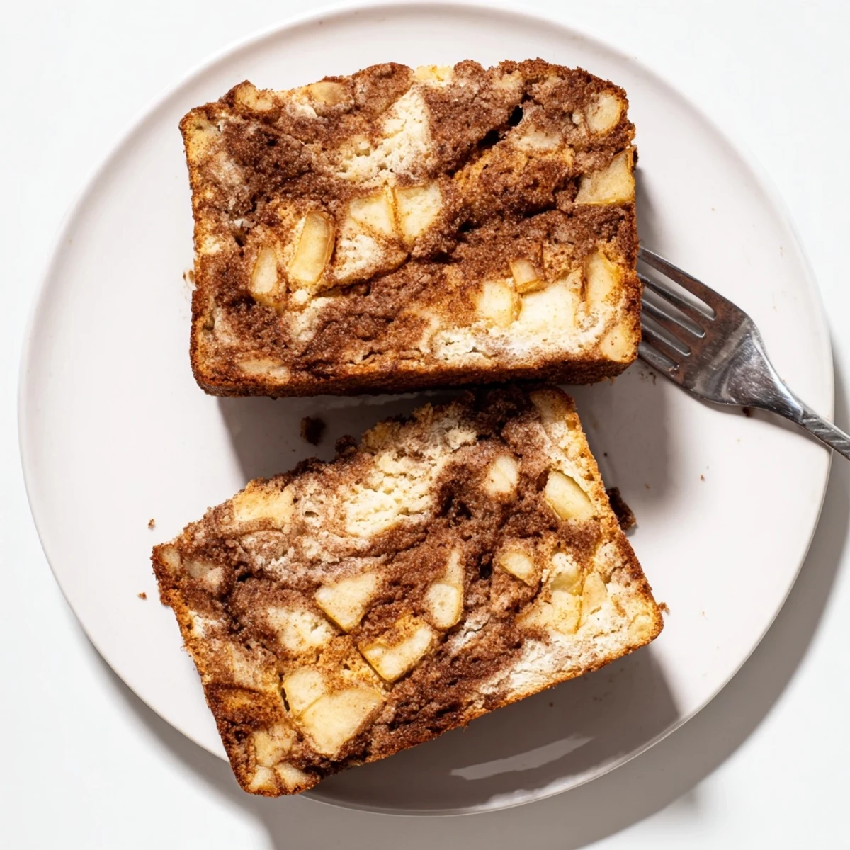Moist cinnamon apple bread slice on a plate with a subtle cinnamon sugar swirl