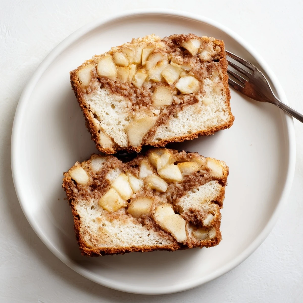 Freshly baked cinnamon apple bread cooling on a wire rack with diced apple pieces visible
