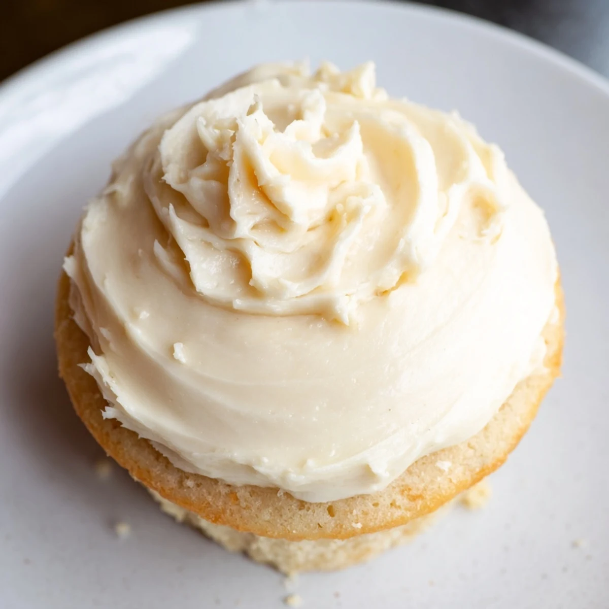 Homemade vanilla cupcakes with tall peaks of buttercream frosting on wire cooling rack