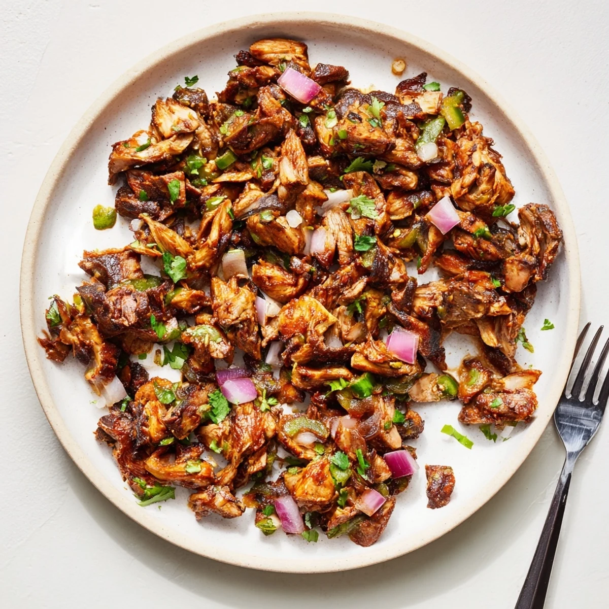 Golden brown vegan carnitas with shredded mushrooms piled in warm corn tortillas