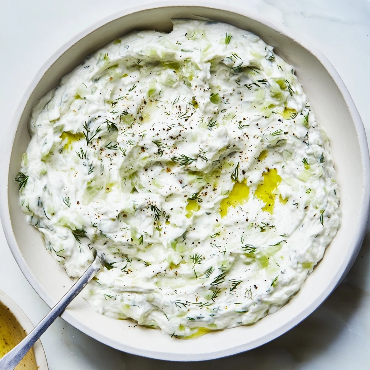 Vibrant healthy radish tzatziki dip topped with olive oil drizzle alongside crisp vegetable crudités for appetizers