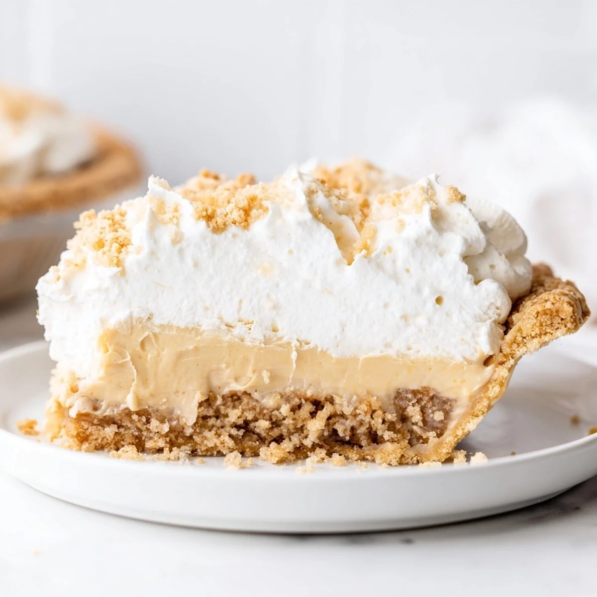 Creamy Amish Peanut Butter Dream Pie topped with fluffy whipped cream and golden crumbs