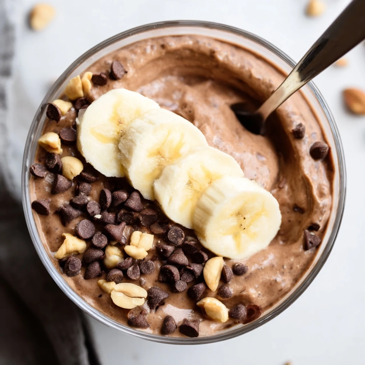 Creamy chocolate peanut butter overnight oats served in a mason jar with banana slices and chocolate chips