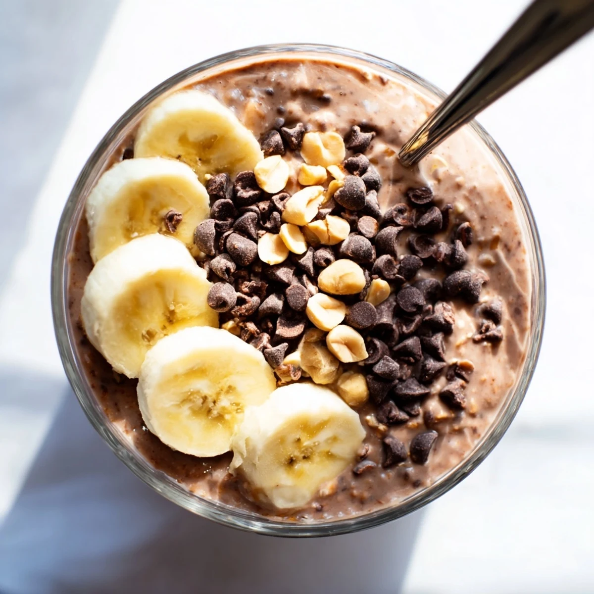 Thick chocolate peanut butter overnight oats topped with crushed peanuts and a drizzle of honey