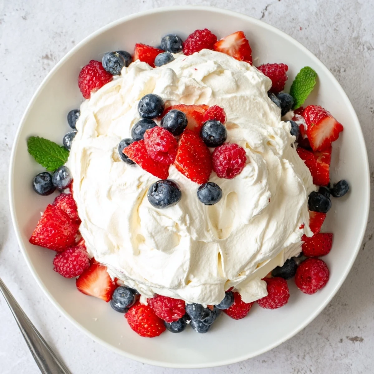 Cool, sweet-tart Red White Blue Cheesecake Salad spooned onto festive serving bowl