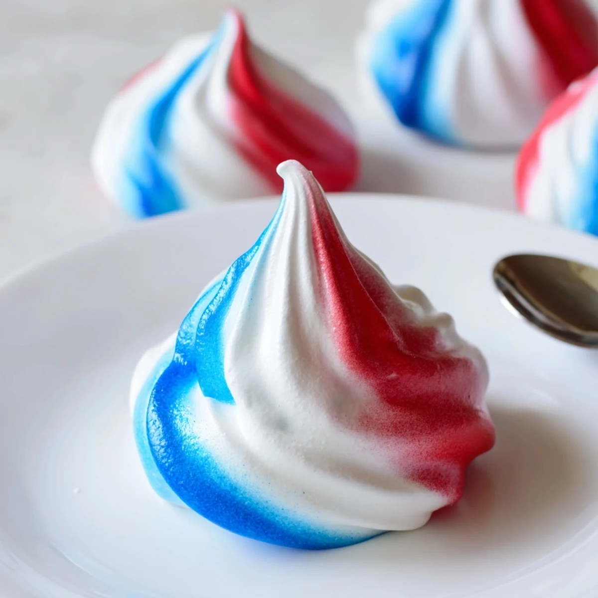 Patriotic Meringue Kisses: crisp red, white, and blue shells cooling on parchment