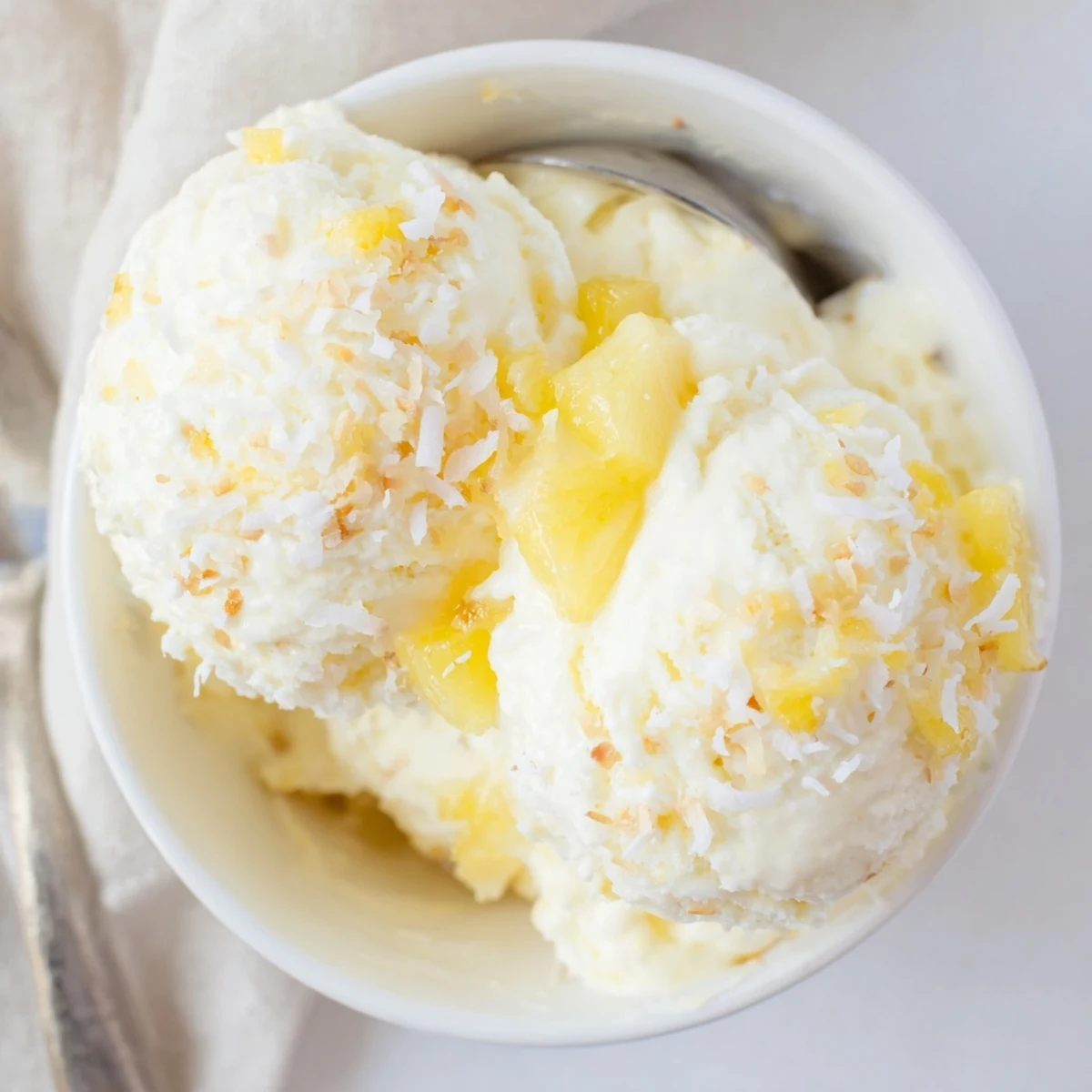 Creamy Pineapple Ice Cream topped with toasted coconut, chilled in bowl.