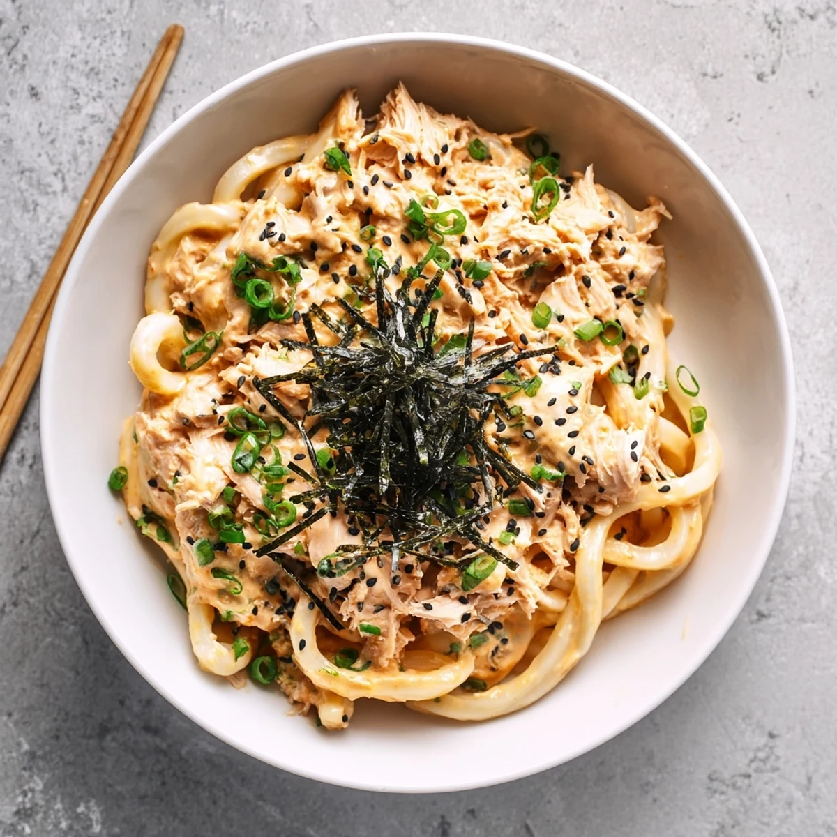 Thick chewy udon noodles tossed in creamy spicy tuna sauce with vibrant green onions