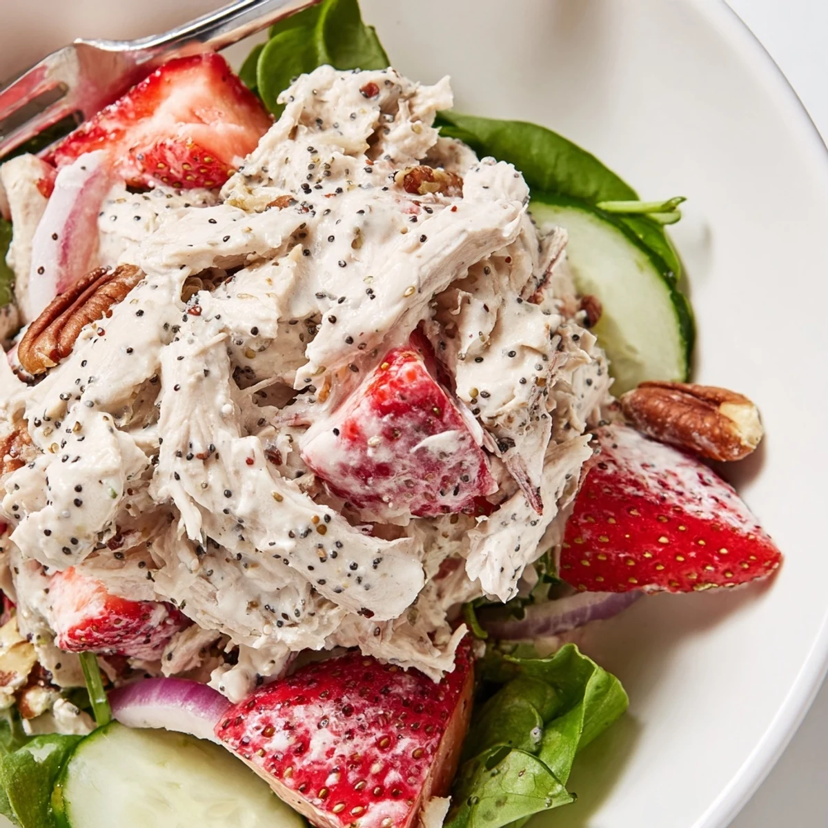 Strawberry Poppy Seed Rotisserie Chicken Salad served on mixed greens, feta, and pecans